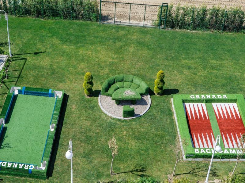 Zewnętrzny taras z stołami do ping-ponga i miejscem do siedzenia na zielonej trawie.