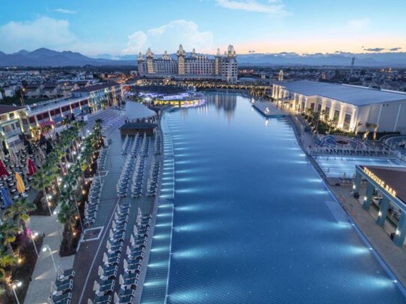 Nocny widok na tętniący życiem kurort z basenami i międzynarodowymi flagami.