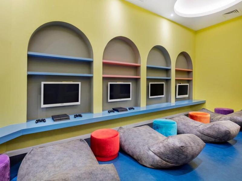 Pokój relaksacyjny z kolorowymi poduszkami i telewizorami w niszach.