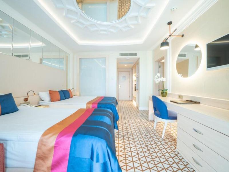 Nowoczesny pokój hotelowy z podwójnym łóżkiem, oświetleniem LED i białymi eleganckimi meblami.