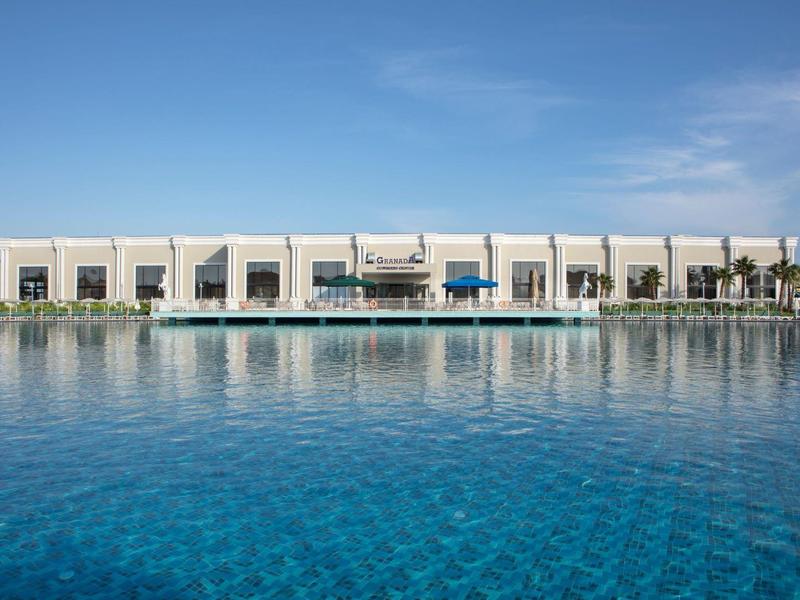 Nowoczesny budynek z spokojnym niebieskim basenem pod jasnym niebem.