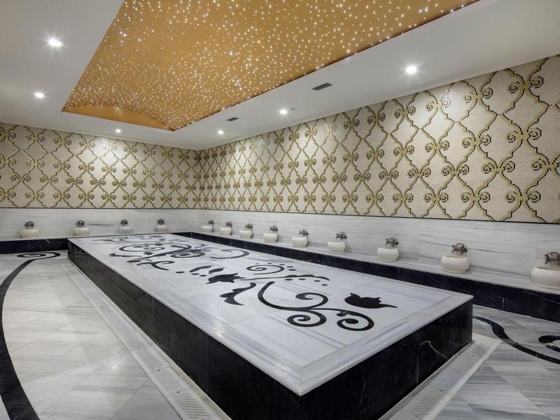 Luksusowa sala spa z marmurowym stołem i złotymi zdobieniami na ścianach.