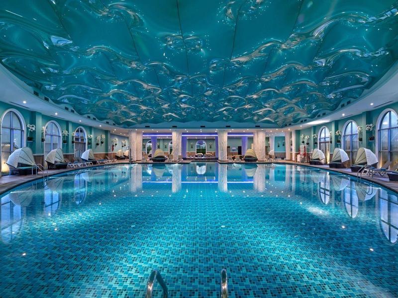 Wewnętrzny basen z sufitem imitującym gwieździste niebo i dużymi łukowymi oknami.