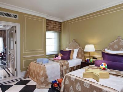 Zwei Einzelbetten in einem elegant eingerichteten Hotelzimmer mit Teppichboden und Nachttischlampen.