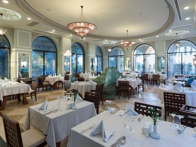 Elegantes Hotelrestaurant mit weißen Tischdecken und großen Fenstern mit Rundbögen.