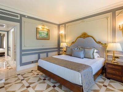 Elegantes Hotelzimmer mit großem Bett, Nachttischlampen und dekorativem Bodenmuster.