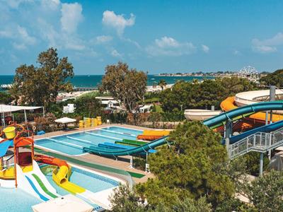 Mehrere Wasserrutschen und Pools in einer Outdoor-Wasserpark-Anlage mit Blick auf das Meer.