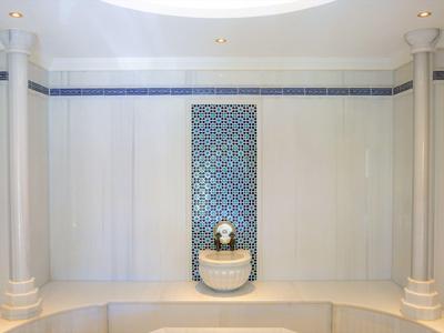 Helle Wellnessoase mit dekorativem Springbrunnen und Säulen in elegantem weiß-blauem Design