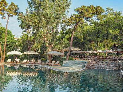 Ruhepool mit Liegestühlen und Schirmen, umgeben von üppigem Grün in einem Resort.