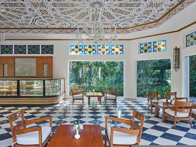 Helle Hotellobby mit gefliesten Böden, dekorativer Decke und Sitzgelegenheiten mit Gartenblick.