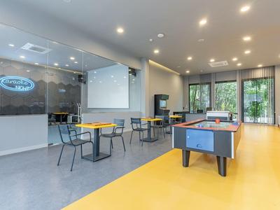 Salon d'hôtel moderne avec tables, chaises et baby-foot dans un espace lumineux.