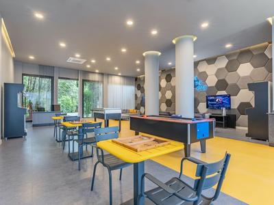 Espace de travail commun moderne dans un hôtel avec table de ping-pong, tables, chaises et grande fenêtre.
