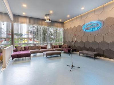 Espace lounge d'hôtel moderne avec fauteuils, micro et grandes fenêtres.
