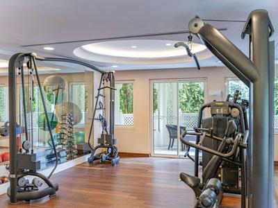 Salle de sport moderne avec équipements de musculation et vue sur terrasse dans un hôtel.