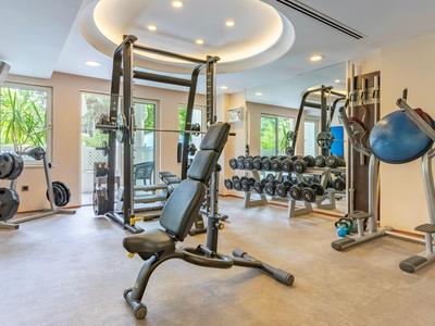 Salle de sport moderne avec appareils d’entraînement, haltères et grandes fenêtres avec vue.