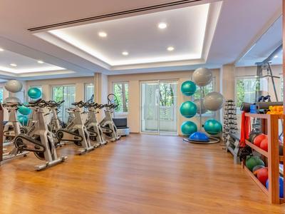 Salle de sport moderne avec vélos de spinning, ballons d'exercice colorés et haltères dans une pièce lumineuse.
