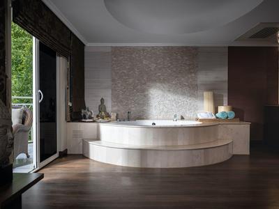 Espace bien-être moderne avec une baignoire ronde et un balcon ouvert donnant sur la verdure.