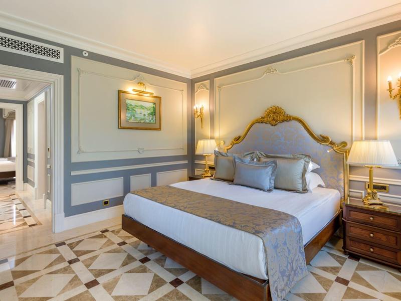 Elegantes Hotelzimmer mit großem Bett, Nachttischlampen und dekorativem Bodenmuster.