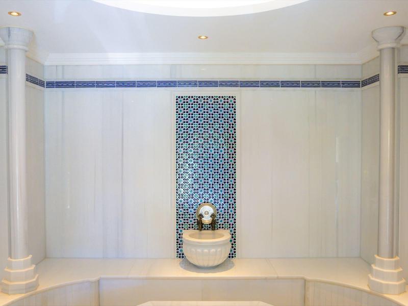 Helle Wellnessoase mit dekorativem Springbrunnen und Säulen in elegantem weiß-blauem Design