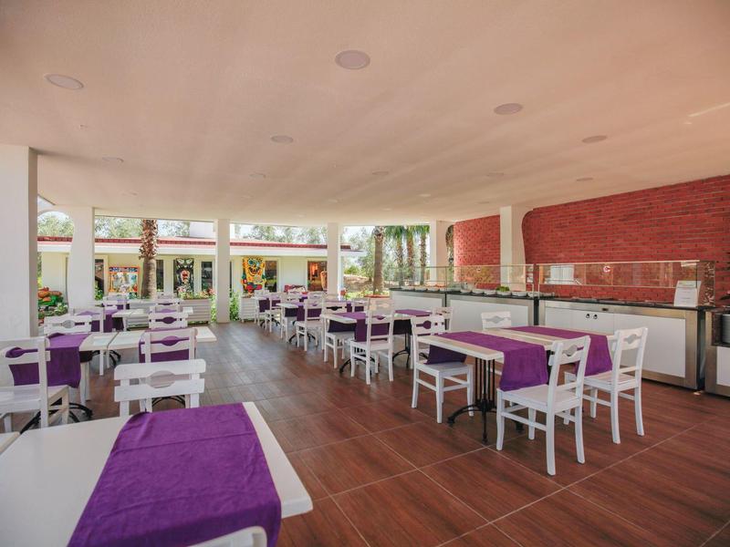 Nowoczesna, otwarta jadalnia z białymi meblami i fioletowymi obrusami w hotelu.