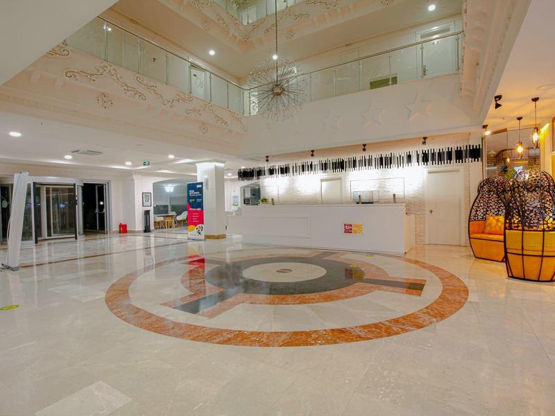 Jasny, nowoczesny hol hotelowy z marmurową podłogą i dekoracyjnymi kulami.