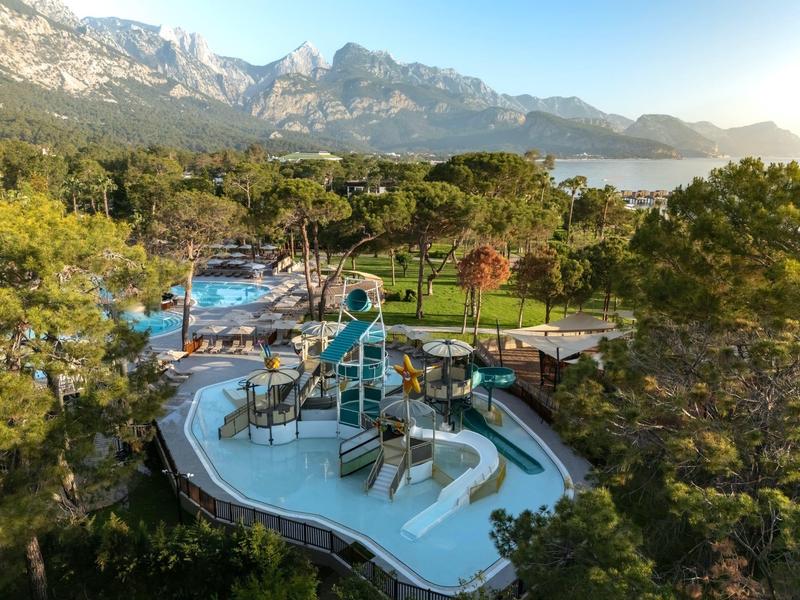 Water park with slides surrounded by trees, mountains, and lake in the background.