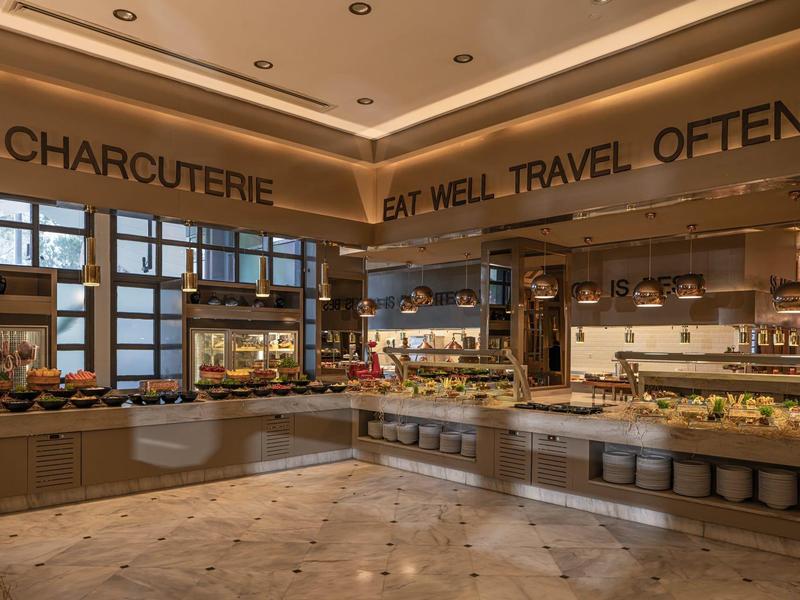 A modern buffet with charcuterie and diverse dishes in an elegant hotel restaurant.