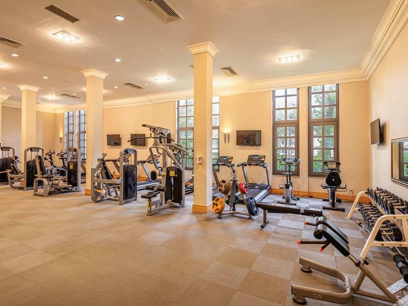 Bright gym with modern equipment and large windows in a hotel.