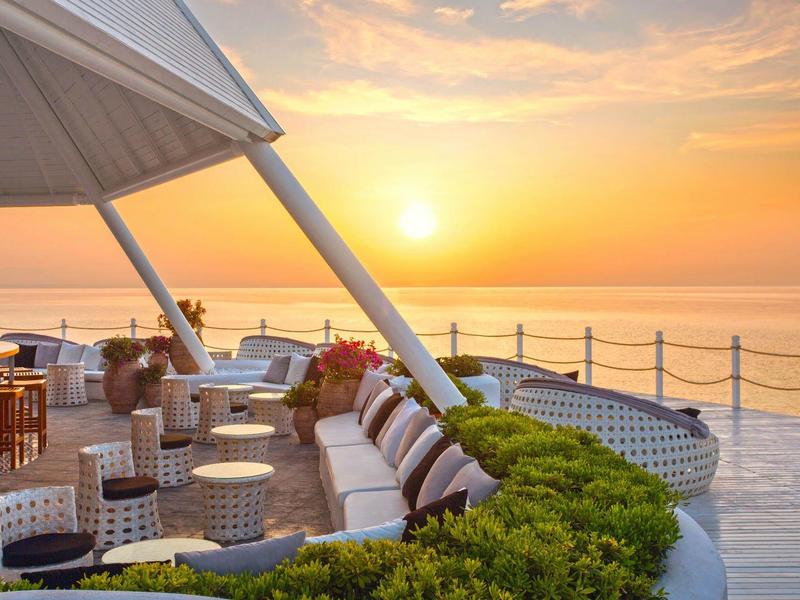 Cozy lounge with seating on terrace at sunset overlooking the sea.
