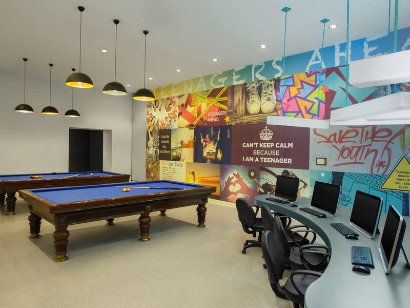 Modern leisure area with pool table, computers, and colorful wall art in a hotel