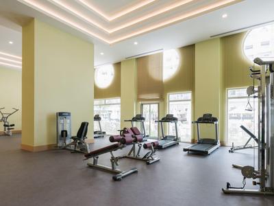 Equipos de fitness modernos y cintas de correr en un gimnasio amplio y luminoso con grandes ventanas.