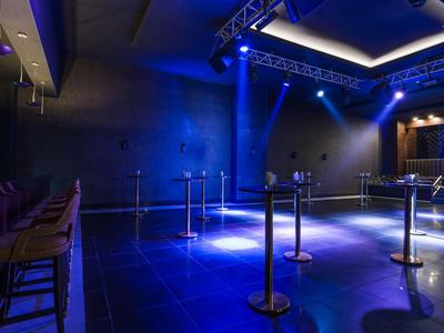 Club nocturno vacío con taburetes de bar e iluminación azul en el escenario