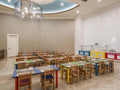 A large, bright room with many small, colorful children's tables and chairs for a daycare.