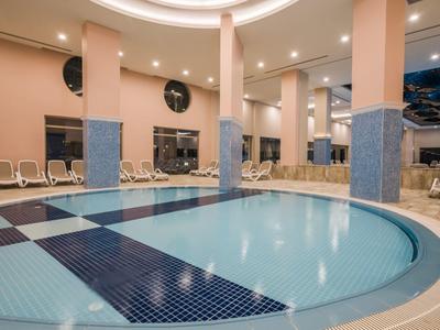 Indoor hotel area with a round jacuzzi and lounge chairs, modern design.
