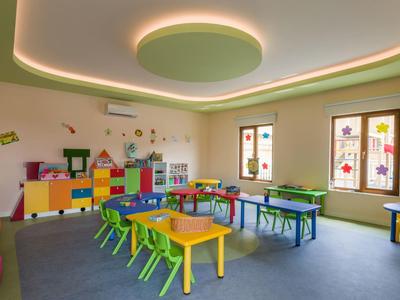 Bright, colorful kindergarten room with small chairs and tables, decorated with window art