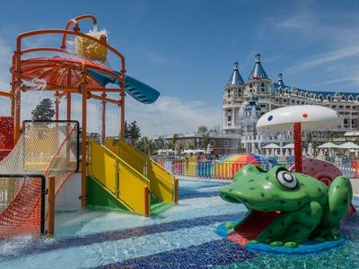 Colorful water park with slides and playful animal figures in front of a large hotel.