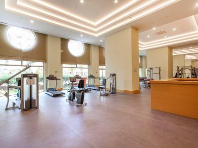 Gimnasio espacioso y luminoso con equipo moderno y ventanas de suelo a techo.