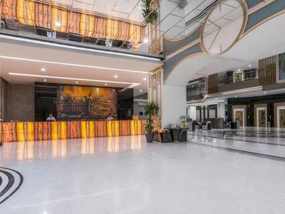 Modern, bright hotel lobby with large reception desk and smooth white floors.