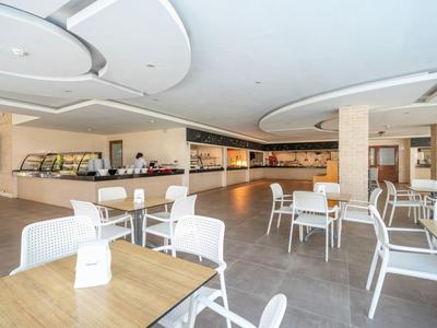 Modern café lounge with white chairs and wooden tables in a bright, open space.
