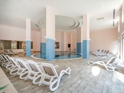 Indoor pool with eight white loungers and light blue pillars in a modern room
