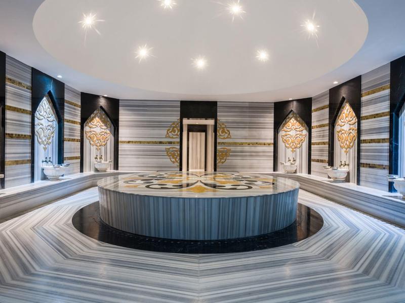Luxury hammam with round marble washbasin and ornate decorative wall panels