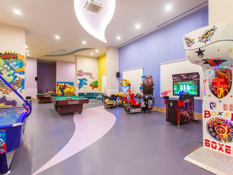 Game room with various arcade and pool tables in a modern, well-lit space.