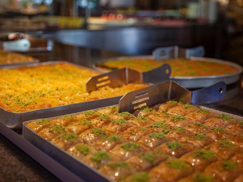 Close-up of trays with different desserts, including baklava, in a restaurant.