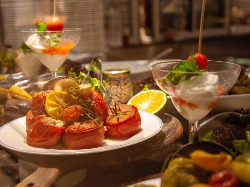 Appetizer plate with stuffed tomatoes and garnish, surrounded by glasses with cocktails.