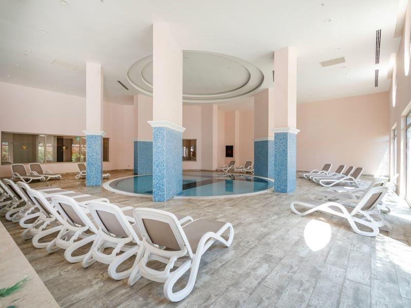 Indoor pool with eight white loungers and light blue pillars in a modern room