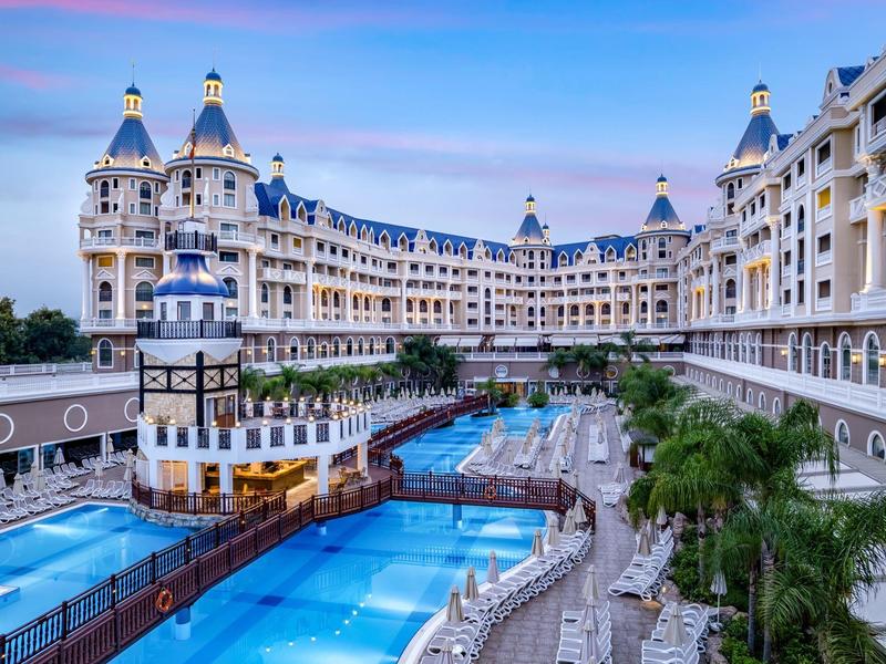 Luxury hotel with multiple swimming pools and elegant architecture at sunset.