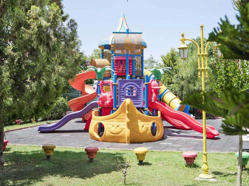 Kolorowy plac zabaw z zjeżdżalniami w zielonym parku w słoneczny dzień.