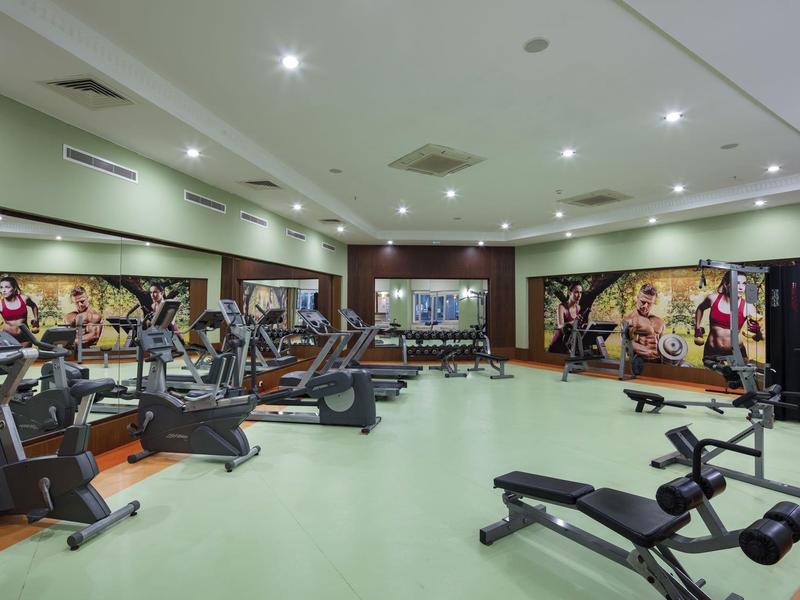 Przestronna siłownia z nowoczesnym sprzętem i muralami ściennymi w hotelu.