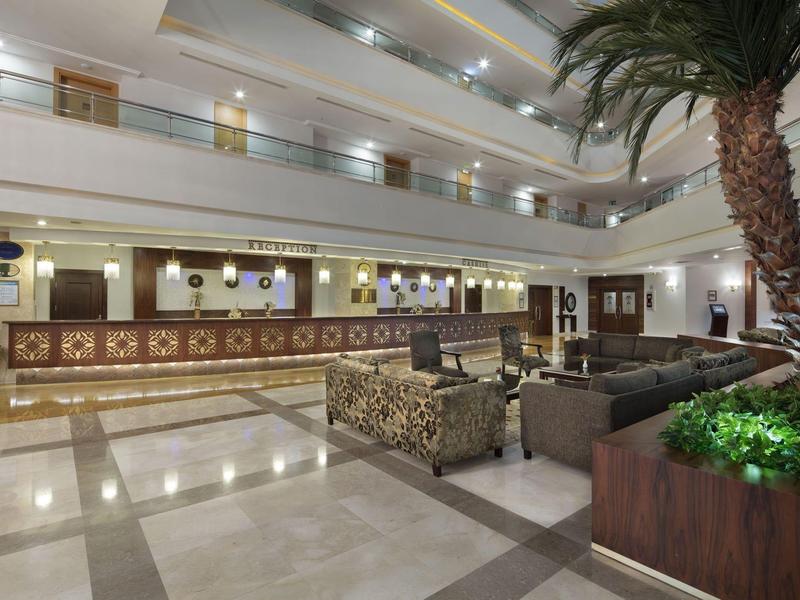 Stylowa, dobrze oświetlona lobby hotelowa z długim recepcją i miejscami do siedzenia.