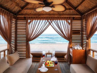 Offene Strandhütte mit gemütlichen Sofas und Blick auf das Meer